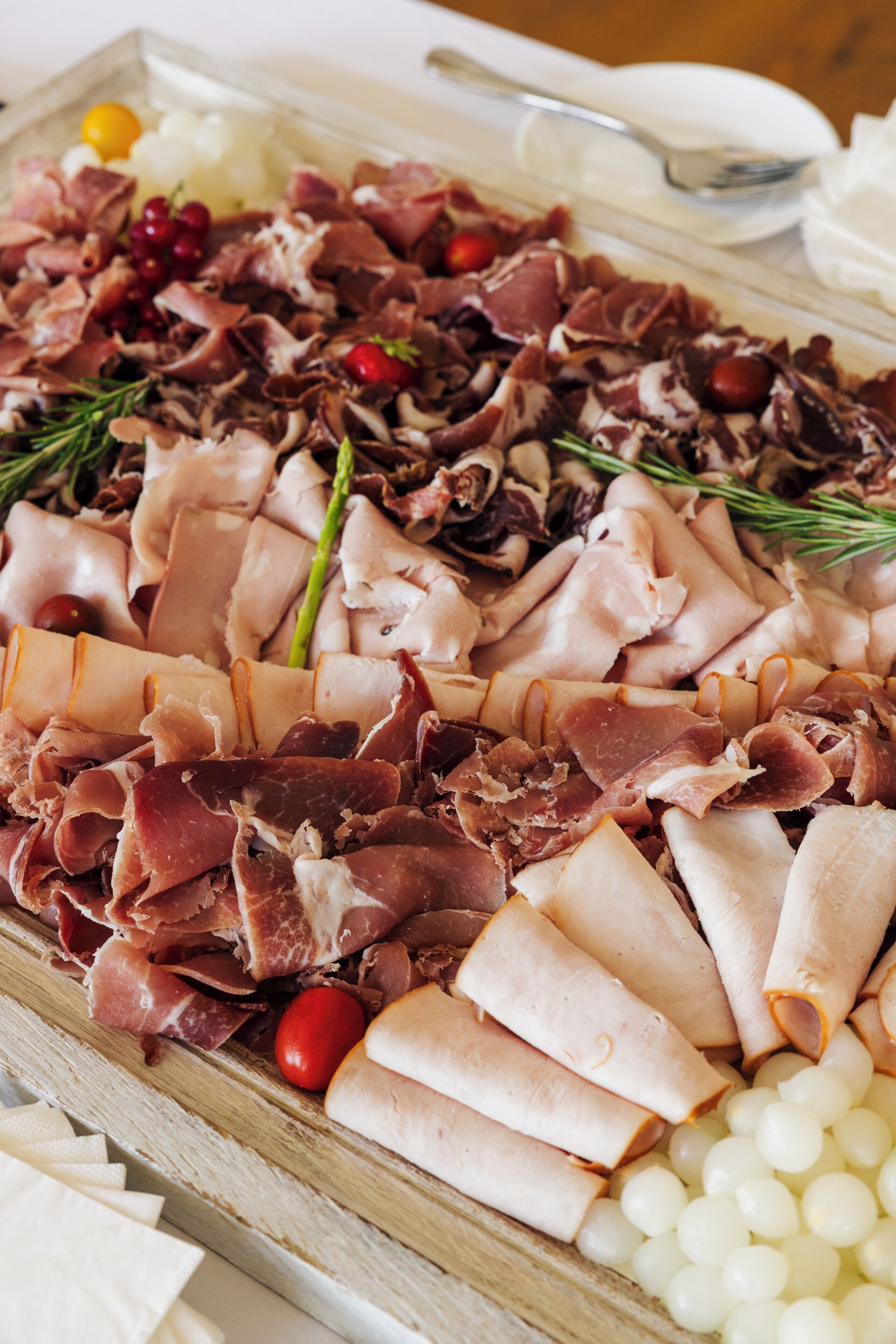 Uma tábua de frios com diversos queijos, carnes e frutas.