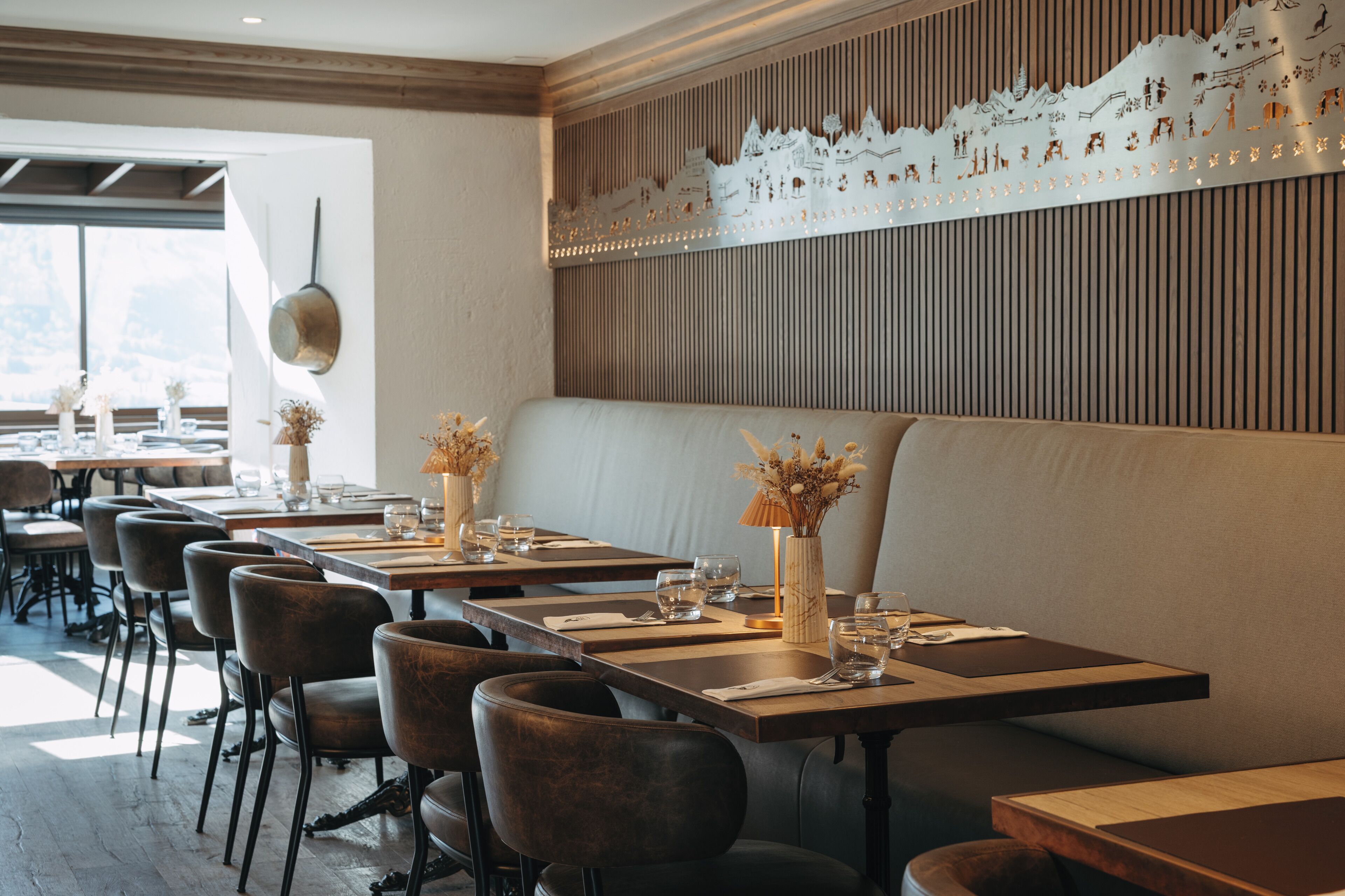 Un restaurante con mesas de madera, asientos acolchados y una pared decorativa.