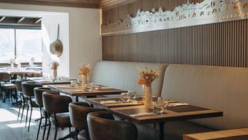 Un restaurante con mesas de madera, asientos acolchados y una pared decorativa.