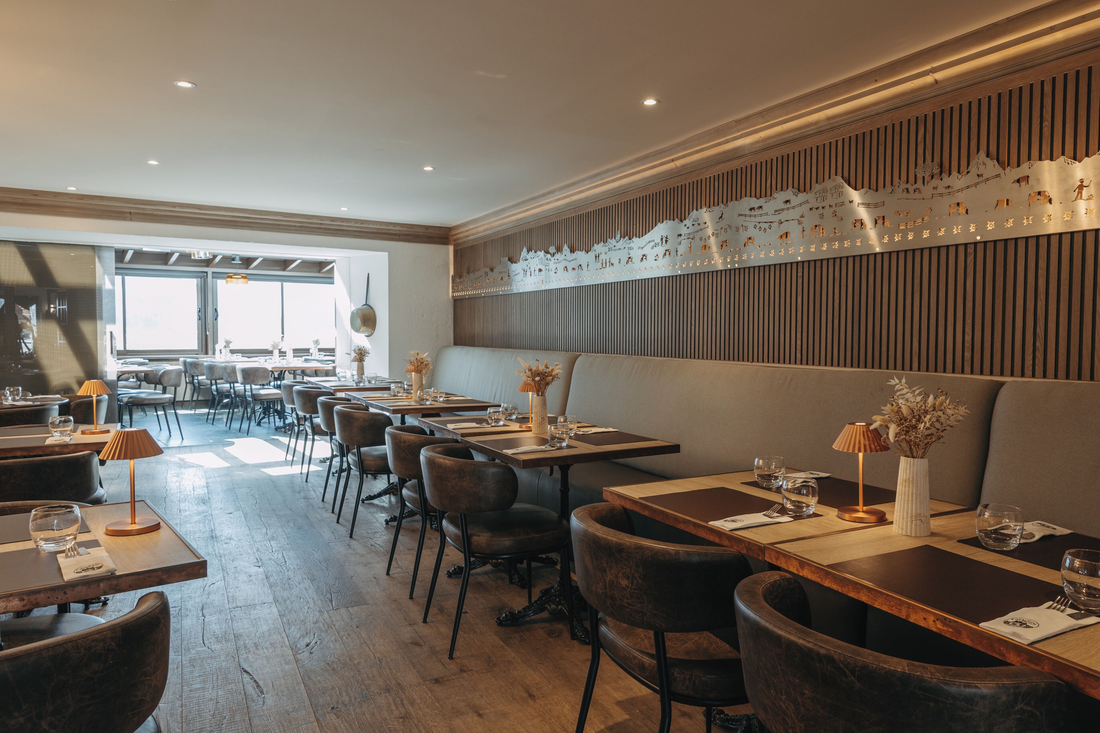 A restaurant interior with wooden tables, chairs, and a decorative wall.