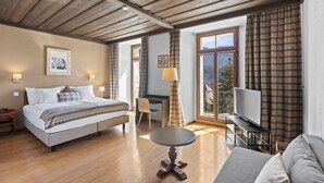 Quarto espaçoso com cama, escrivaninha, televisão e vista para a varanda.