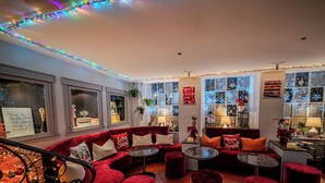 A cozy lounge area with red velvet sofas, round tables, and Christmas decorations. - ROESLI Guest House (Lucerne)