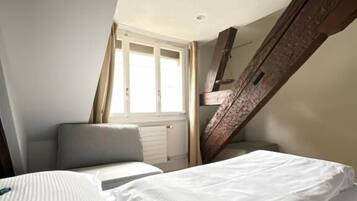 Ein Schlafzimmer mit Bett, Fenster und Holzbalken.