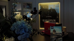 A reception desk with a 'Welcome' sign, a city guide book, and a vase of flowers. - ROESLI Guest House (Lucerne)