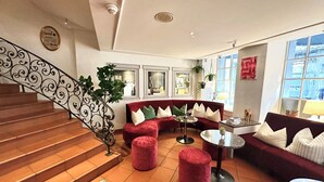 A spacious living area with a red sofa, a coffee table, and a staircase with a decorative railing. - ROESLI Guest House (Lucerne)