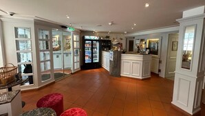 A hotel lobby with a reception desk, seating area, and a refrigerator with beverages. - ROESLI Guest House (Lucerne)
