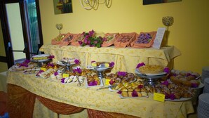 A buffet table with various pastries and desserts, arranged on a patterned tablecloth. - Villa Fiorentino (Lipari)