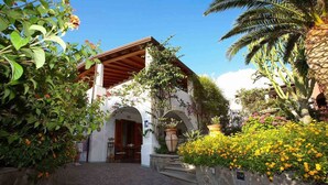 A traditional building with a tiled entrance, a wooden roof, and a stone wall. - Villa Fiorentino (Lipari)