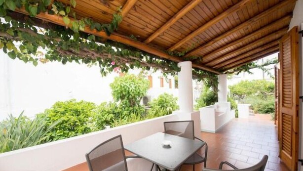 An outdoor patio with a wooden pergola, two tables, and chairs.