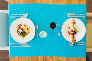 A table with two plates of food, a glass of red drink, and cutlery. - Sentido Fido Punta del Mar Hotel & Spa (Calvia)