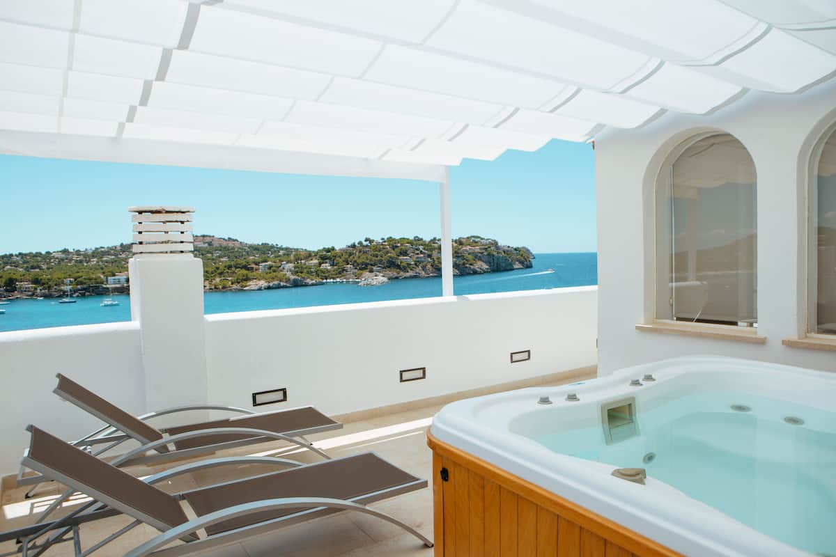 A balcony with a hot tub, lounge chairs, and a view of the sea.