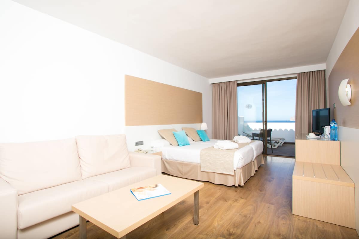 A hotel room with a bed, a sofa, a desk, and a TV.
