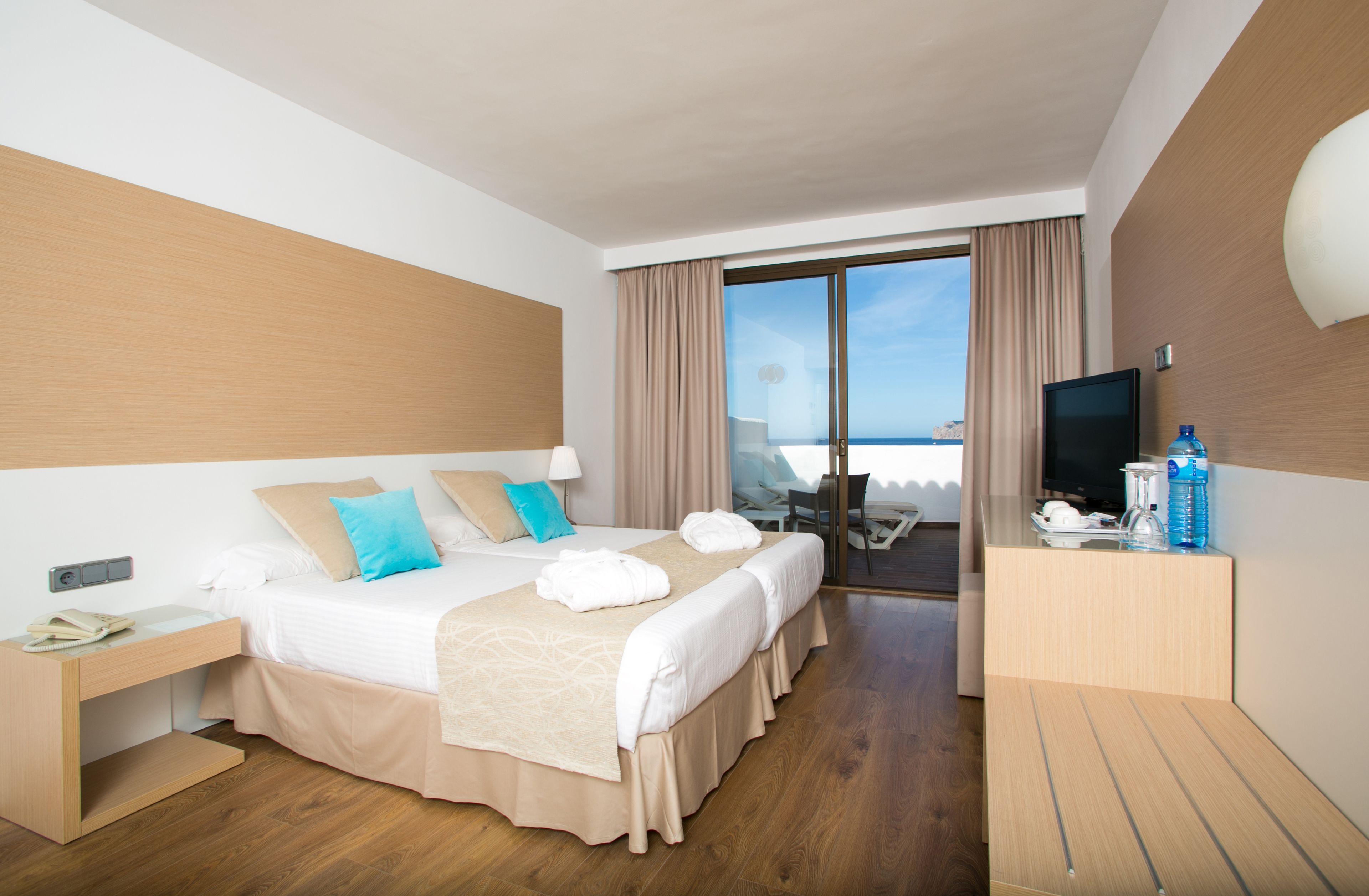 Habitación de hotel con una cama grande, escritorio, televisor y vista al mar.