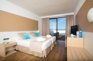 Habitación de hotel con una cama grande, escritorio, televisor y vista al mar.