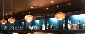 Una zona de bar con lámparas esféricas colgantes y estantes que exhiben diversas botellas de licores.