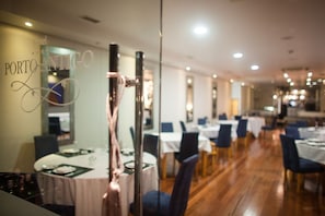 Un restaurante con mesas dispuestas para comer, una pared de cristal con un adorno, y un letrero que indica que es un hotel.