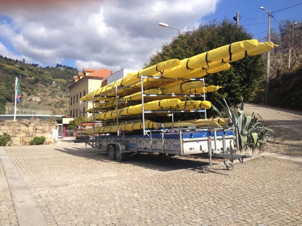 A truck loaded with yellow kayaks parked on a cobblestone street.