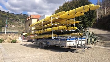 A truck loaded with yellow kayaks parked on a cobblestone street.