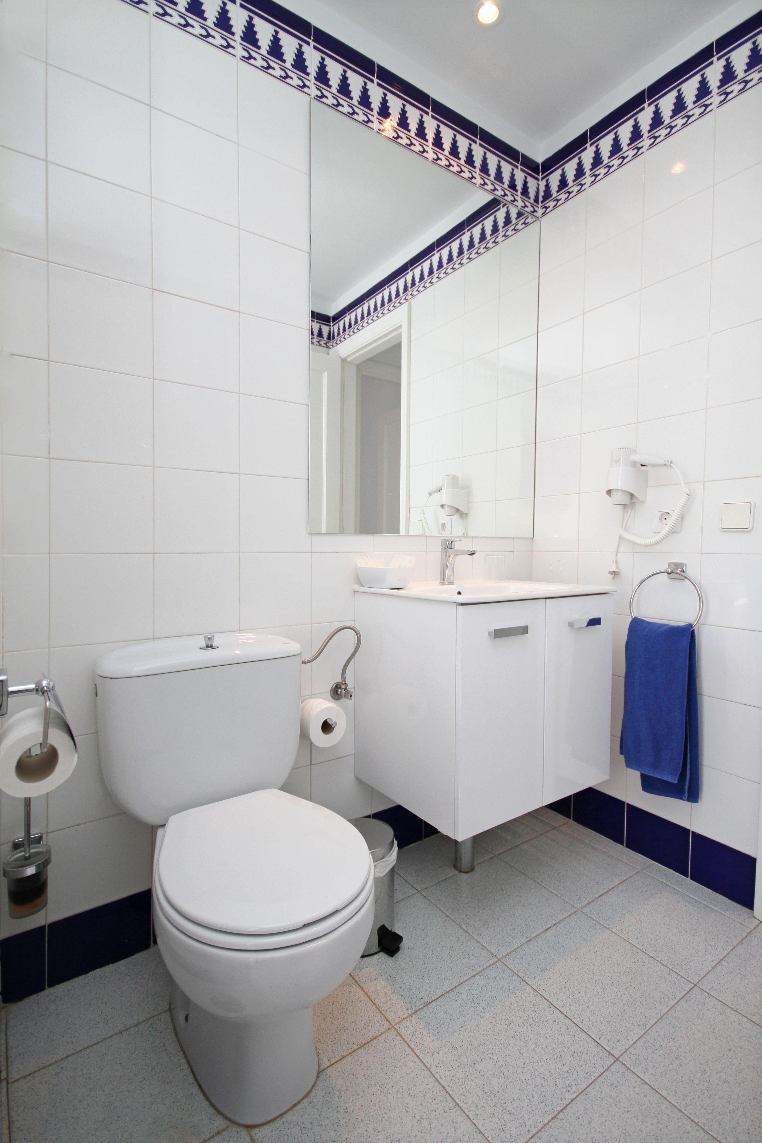 A bathroom with a toilet, sink, and mirror.