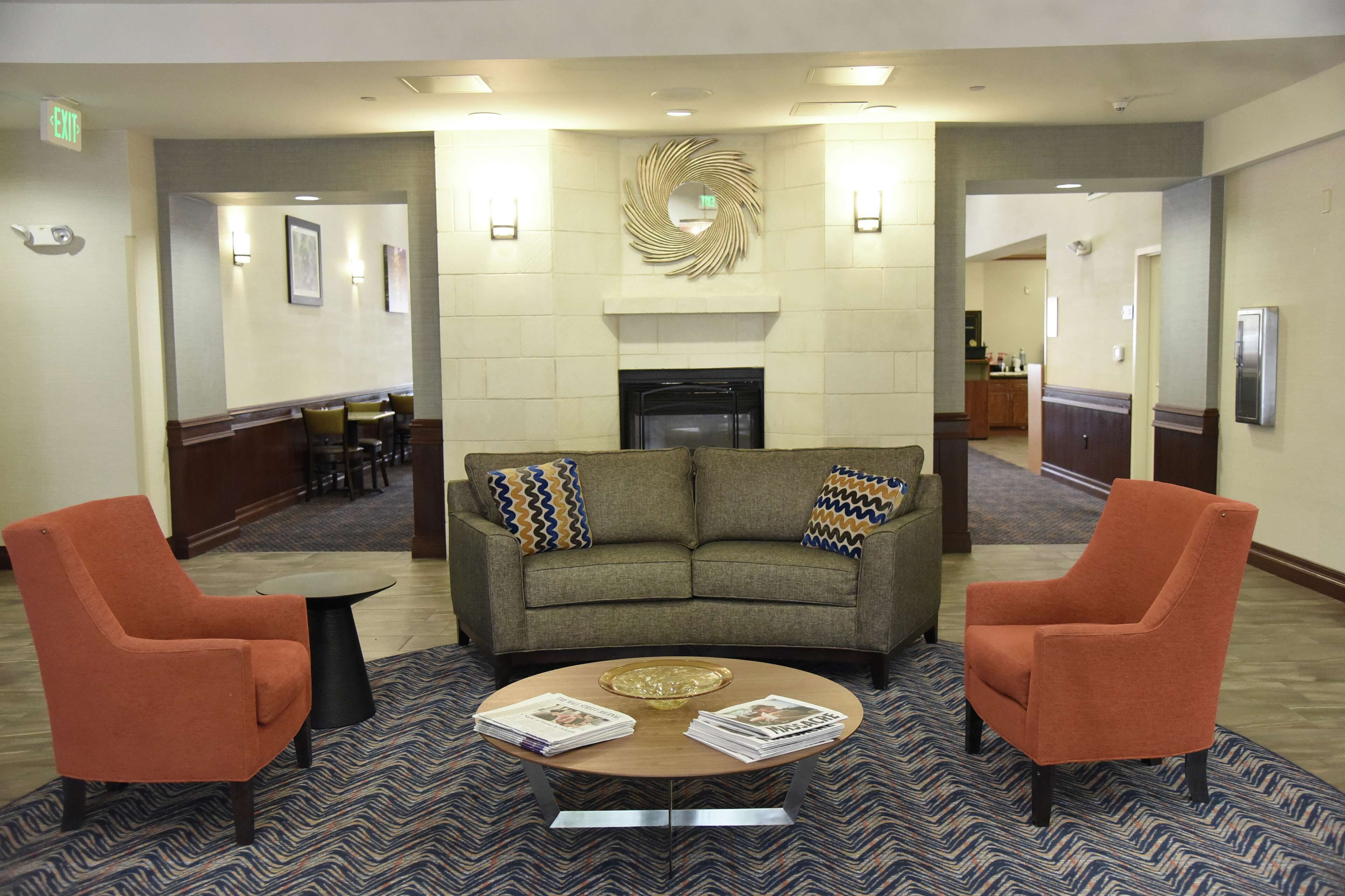 A lobby with a sofa, two armchairs, a coffee table, and a fireplace.