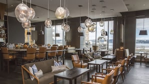 Un restaurante moderno con zona de bar, asientos de cuero y grandes ventanales con vistas.