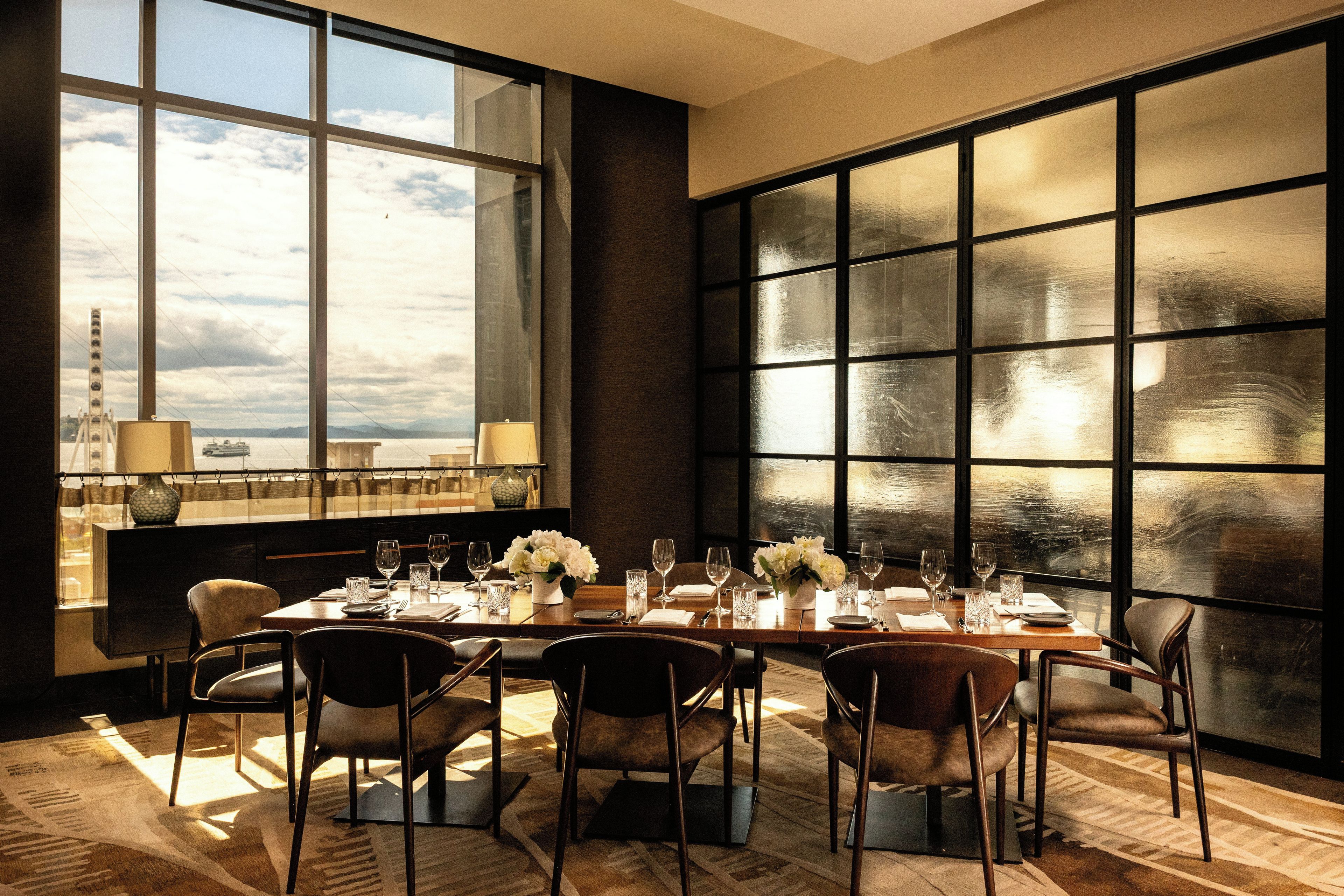 Comedor con una mesa grande dispuesta para seis personas, ventanas amplias y vista a un puente.