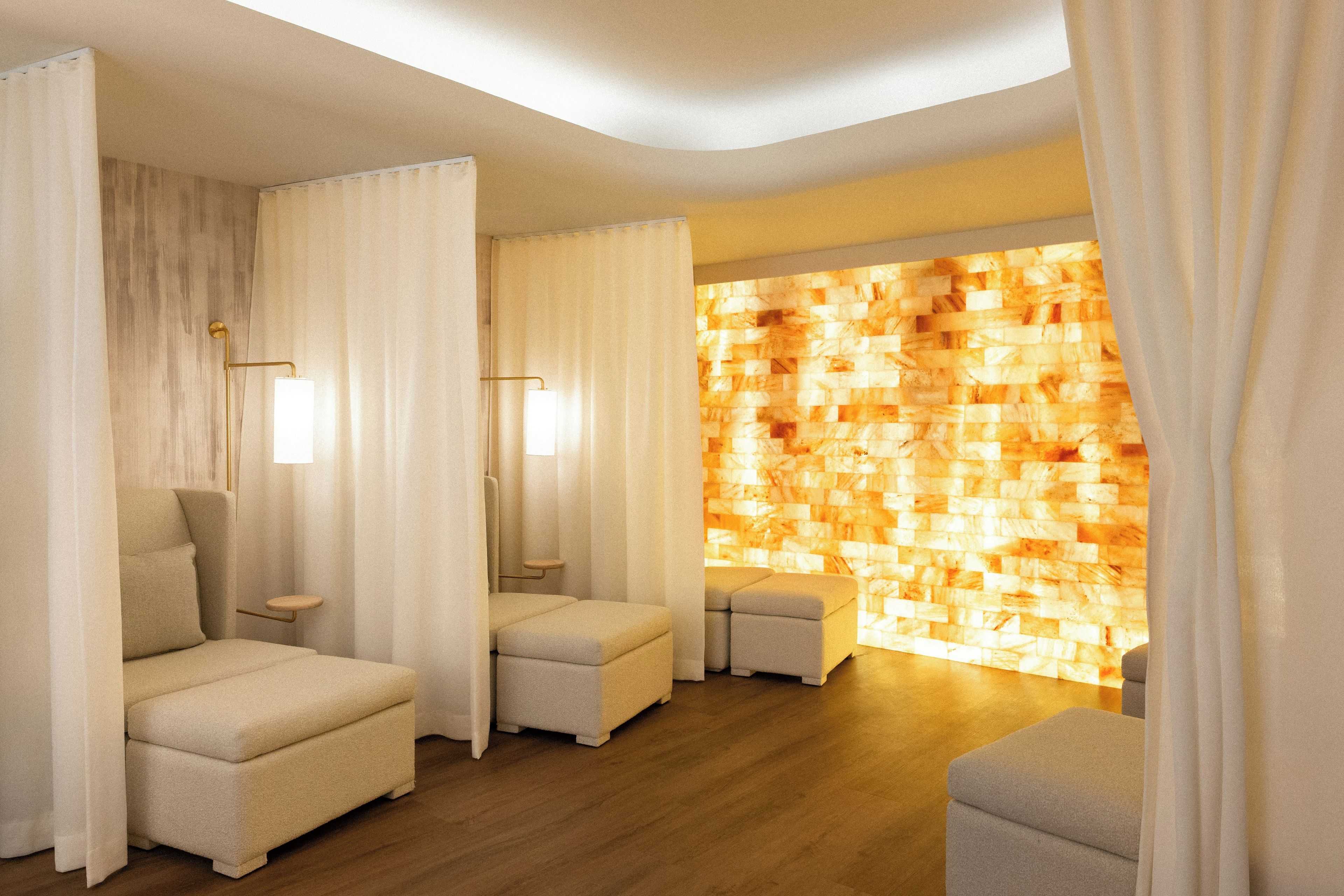 A spa room with two cushioned seating areas, a wooden floor, and a wall with a textured pattern.