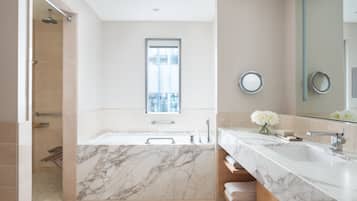 A modern bathroom with a large marble sink, a bathtub, and a shower.