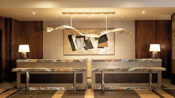 A reception desk with two lamps, a hanging abstract artwork, and a patterned floor.