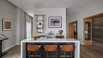 A modern kitchen with a central island, bar stools, a wine rack, and a framed painting.