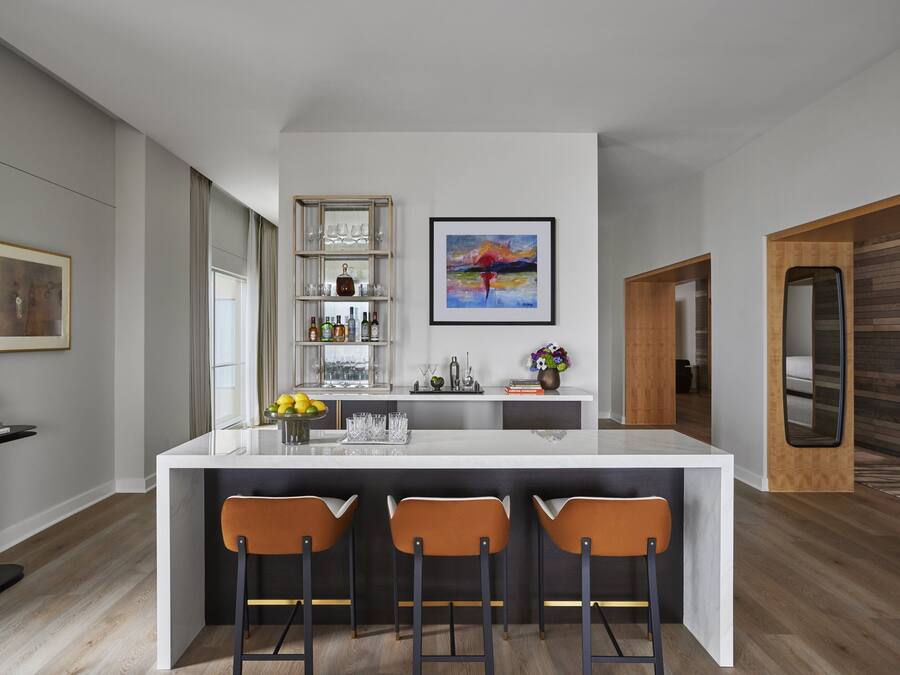 A modern kitchen with a central island, bar stools, a wine rack, and a framed painting.