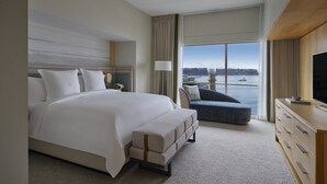 A hotel room with a large bed, a seating area, a television, and a view of the water. - Four Seasons Hotel Seattle (Seattle)