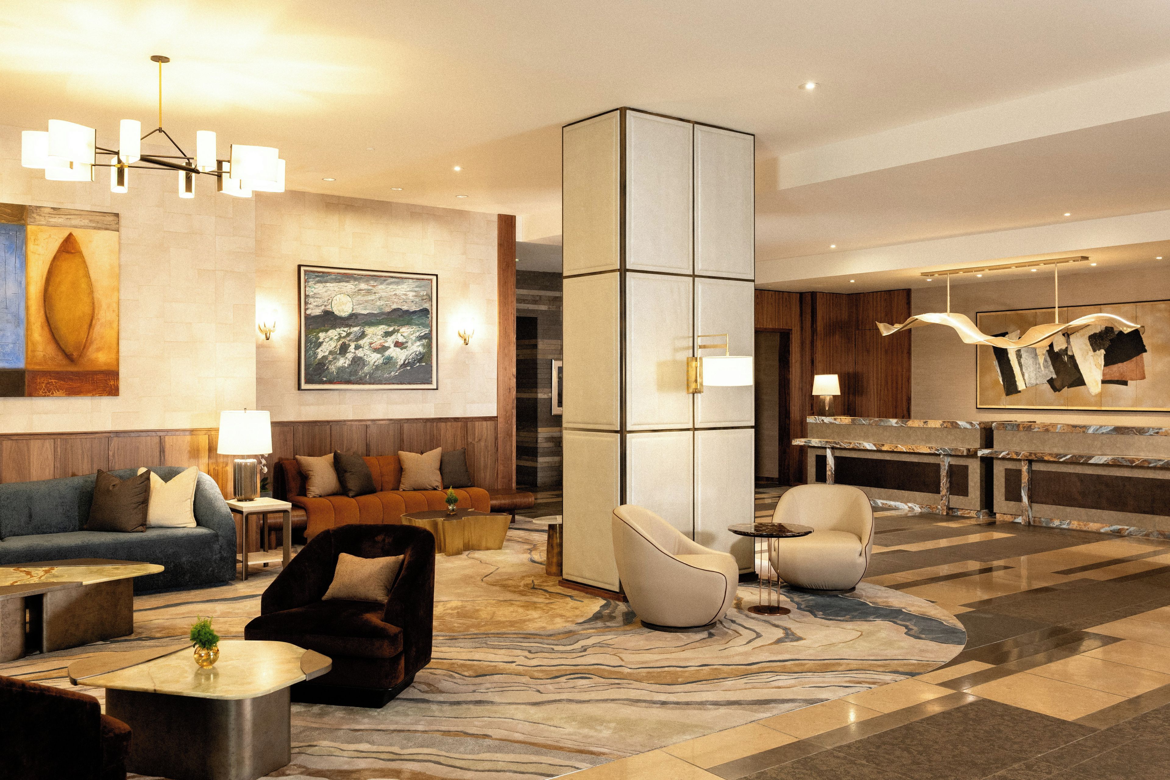A modern hotel lobby with a seating area, a fireplace, and a reception desk.