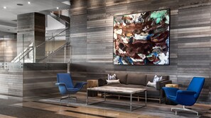 A modern lobby with a staircase, a large abstract painting, and contemporary furniture.