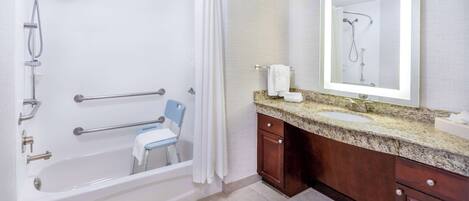 A bathroom with a bathtub, shower, and a vanity with a mirror.