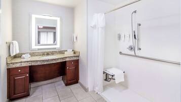A bathroom with a vanity, sink, mirror, shower, and towel rack.