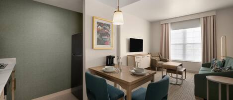 Habitación de hotel con comedor, kitchenette, televisor de pantalla plana, sofá y ventana con cortinas.