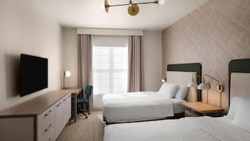 A hotel room with two beds, a desk, a chair, a TV, and a window with curtains.