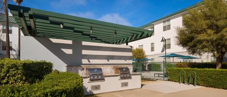 An outdoor barbecue area with a grill and a pergola.