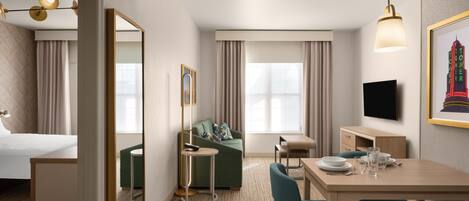 Une chambre d’hôtel comprenant un lit, un canapé, une table à manger avec des chaises, un téléviseur et un tableau encadré au mur.