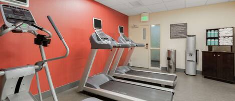 A fitness center with treadmills, a water dispenser, and a sign indicating the exit.