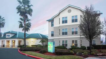 A hotel with a sign for Homewood Suites, a parking lot, and a building with a green roof.