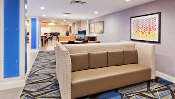 Un hall de hotel con una zona de estar, una recepción y un comedor.