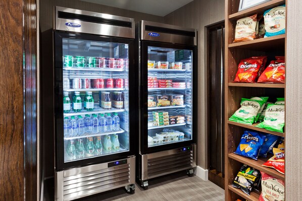 Dos vitrinas refrigeradas repletas de bebidas y aperitivos, incluyendo agua embotellada, refrescos y diversos alimentos envasados.