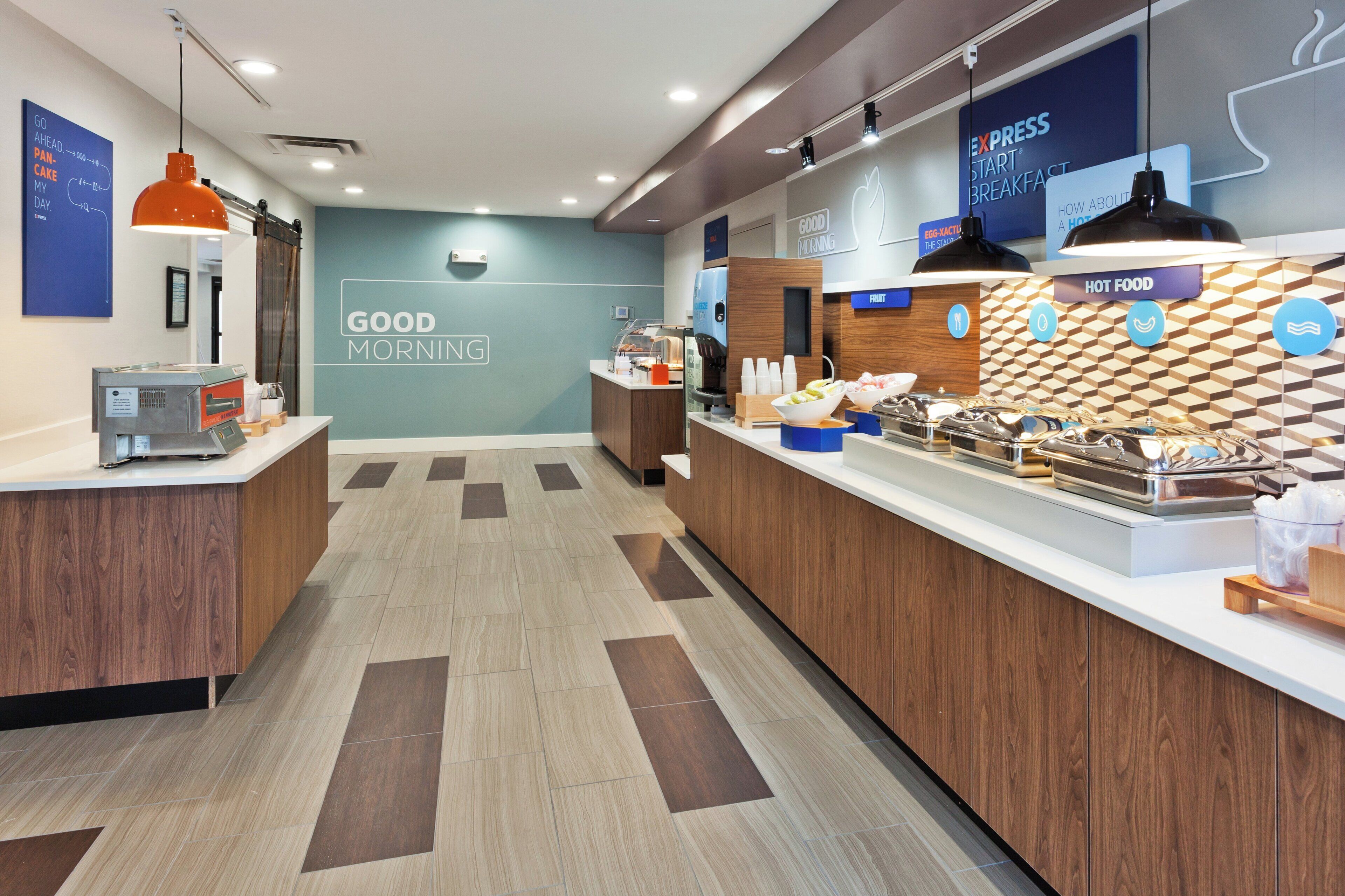A modern breakfast area with a counter displaying various food items and a sign that reads 'GOOD MORNING'.