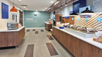 A modern breakfast area with a counter displaying various food items and a sign that reads 'GOOD MORNING'.