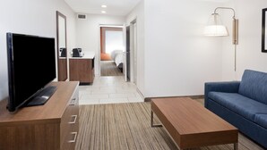 Een moderne hotelkamer met een flatscreen televisie, een houten bureau, een blauwe bank en een lamp.