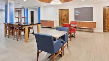 Een moderne eetruimte met houten tafels en stoelen, een blauwe accentmuur en een bordje met koffieservice.