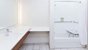 Een moderne badkamer met een wit wastafel, spiegel en douchegedeelte.