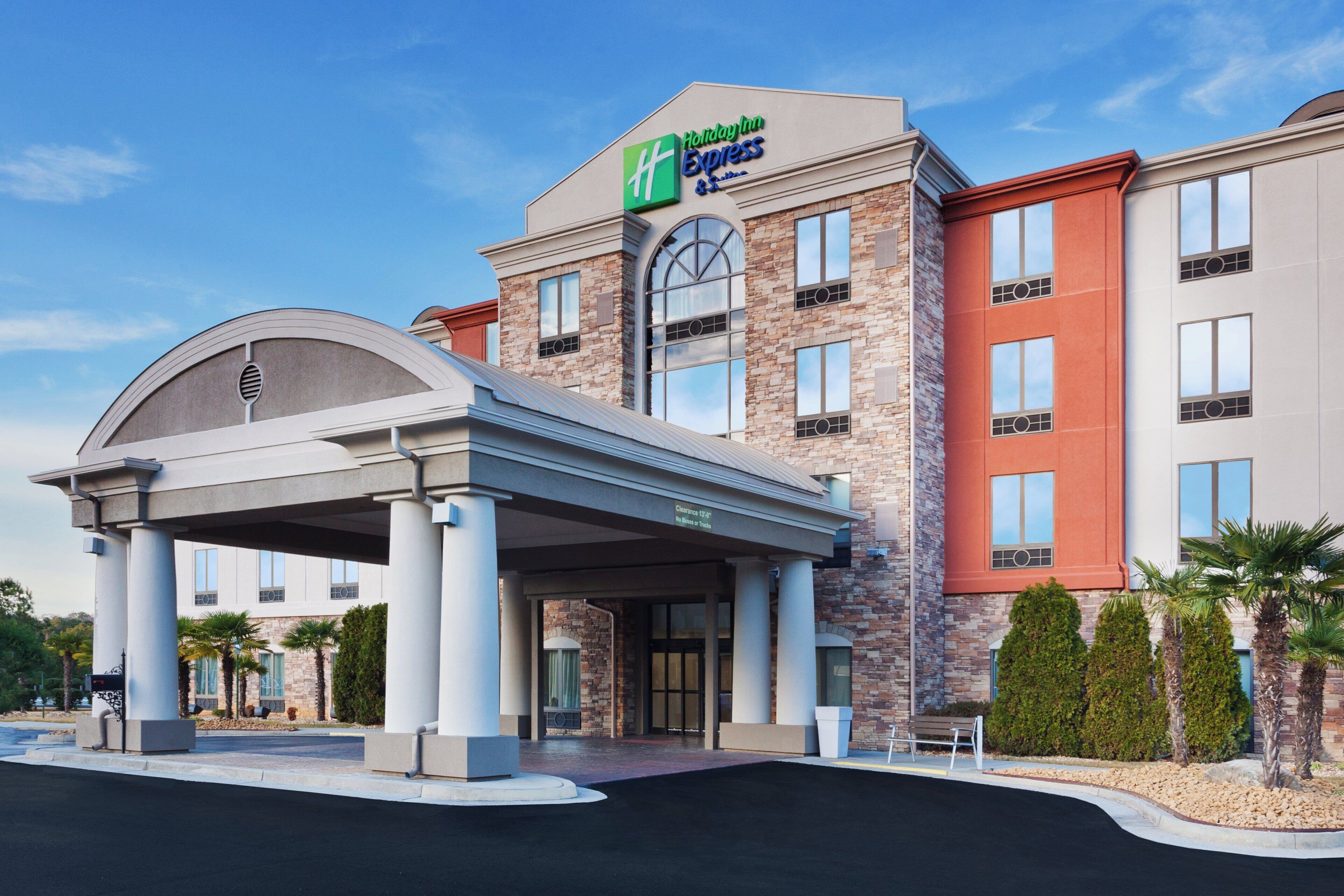 Een Holiday Inn Express hotel met een overdekte ingang, een gevel van natuursteen en een heldere lucht.